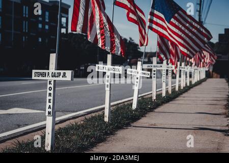 DULUTH, STATI UNITI - 07 novembre 2020: Duluth, Georgia / Stati Uniti - 6 novembre 2020: Croci bianche e bandiere americane fiancheggiano una strada cittadina in memor Foto Stock