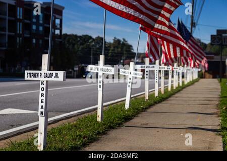 DULUTH, STATI UNITI - 07 novembre 2020: Duluth, Georgia / Stati Uniti - 6 novembre 2020: Croci bianche e bandiere americane fiancheggiano una strada cittadina in memor Foto Stock