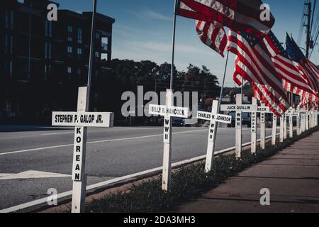 DULUTH, STATI UNITI - 07 novembre 2020: Duluth, Georgia / Stati Uniti - 6 novembre 2020: Croci bianche e bandiere americane fiancheggiano una strada cittadina in memor Foto Stock