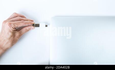 Maschio inserisce una scheda USB compatta nell'ingresso corrispondente sul lato del netbook bianco. Foto Stock