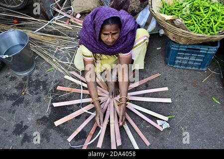 Udaipur, Rajasthan, India - Ottobre, 2016: Donna indiana che fa il cesto di vimini sul mercato di strada. Contenitore tradizionale realizzato a mano in materiale di paglia. Foto Stock