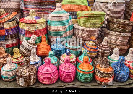 molti cesti di paglia africani su uno stand mercato, con molti colori e decorazioni Foto Stock