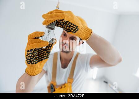 Manipolo in una lampadina gialla uniforme che cambia luce. Ristrutturazione casa concezione Foto Stock