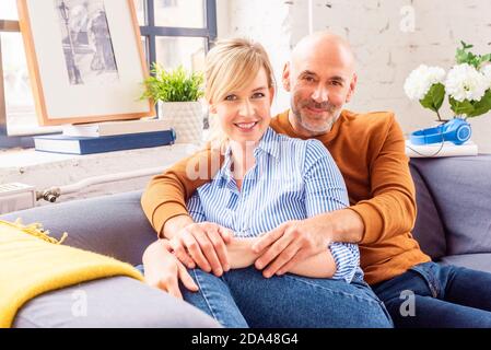 Foto di una coppia felice seduta sul divano a casa e che si lega l'una all'altra mentre ci si rilassa a casa. Foto Stock