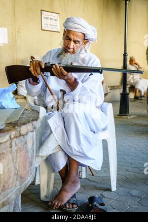 Nizwa, Oman, 2 dicembre 2016: Un anziano sta ispezionando un fucile da caccia al mercato delle armi del venerdì a Nizwa, Omam Foto Stock