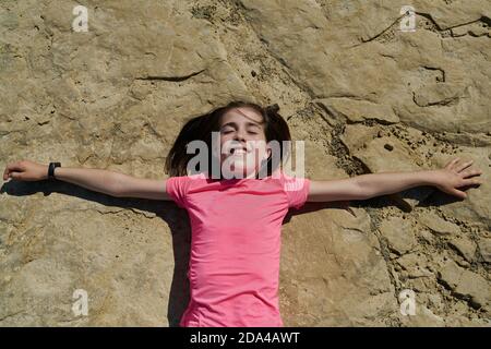 Ragazza che indossa una blusa rosa sdraiata su una roccia nel Bardenas Reales National Park a Navarra, Spagna. Concetto di turismo Foto Stock