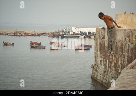 El Jadida, Marocco 2007 agosto. I giovani giocano saltando dalle mura della città al mare. Foto Stock