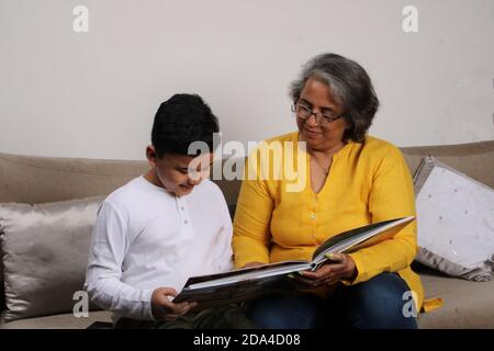 Momenti felici con la nonna, signora superiore indiana/asiatica che passa il tempo di qualità con il suo libro di lettura del figlio grande insieme. Foto Stock