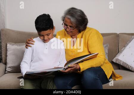 Momenti felici con la nonna, signora superiore indiana/asiatica che passa il tempo di qualità con il suo libro di lettura del figlio grande insieme. Foto Stock