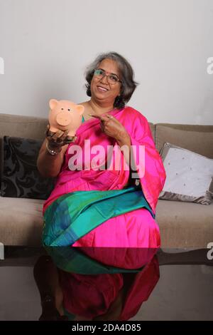 Signora indiana/donne con banca piggy. Foto Stock