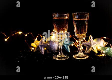 Capodanno e Natale decorazione nel buio. Bicchieri per champagne, giocattoli per l'albero di Natale stand sul tavolo di fronte al buio Foto Stock