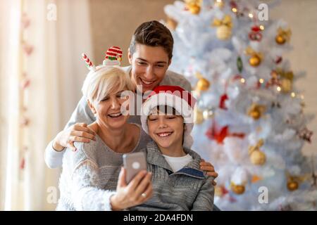 Madre e figli che prendono selfie a una festa di Natale a. casa Foto Stock