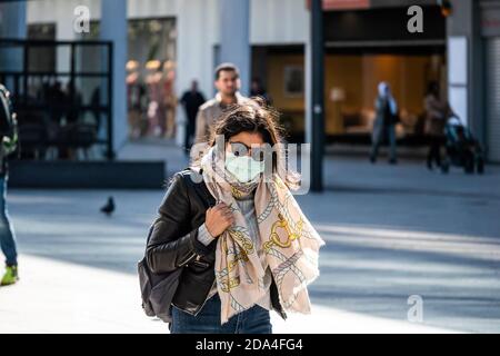 Primavera 2020. Francoforte, Germania. Donna che cammina all'aperto in città indossando la maschera facciale. Scatto medio. Foto Stock