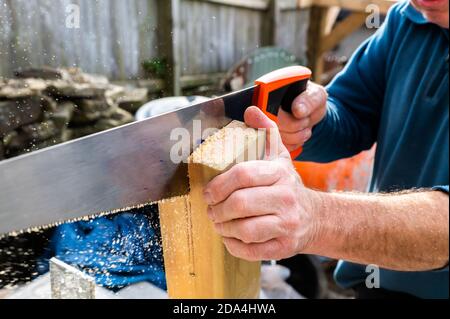 Manipolo con sega manuale che taglia una fessura nel corrimano montante da montare sulla staffa Foto Stock