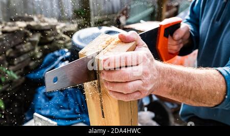 Manipolo con sega manuale che taglia una fessura nel corrimano montante da montare sulla staffa Foto Stock