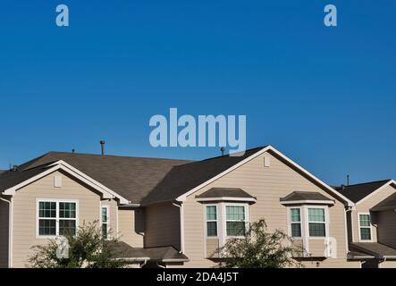 Townhome tetti nei sobborghi in una suddivisione della città sotto un cielo blu chiaro con spazio di copia sopra. Foto Stock