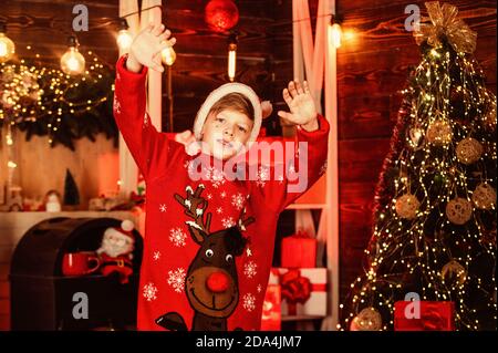 Ciao santa. Little Boy in rosso le renne maglione. kid a santa claus hat divertirsi a casa. Buon Natale a tutti. Vuole xmas presente. le migliori vacanze invernali. Felice adolescente di celebrare la festa di capodanno. Foto Stock