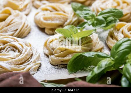 Pasta alluovo, Tagliatelle o fettuccine. Palline rotonde di pasta cruda sul tagliere di legno su sfondo nero Foto Stock