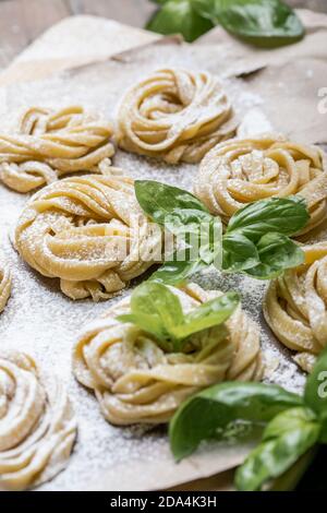 Pasta alluovo, Tagliatelle o fettuccine. Palline rotonde di pasta cruda sul tagliere di legno su sfondo nero Foto Stock