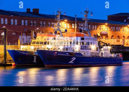 La polizia costiera di Amburgo pattuglia le barche nel porto di Cuxhaven, in Germania, durante la notte Foto Stock