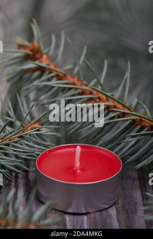 Rami di abete blu su assi di pino spazzolato. Nelle vicinanze si trova una candela rossa. Primo piano. Foto Stock