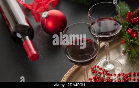 Vino rosso di Natale. Due bicchieri da vino in un vassoio d'argento pronto a servire, decorazioni natalizie sul tavolo, vista closeup. Vacanze invernali cel Foto Stock