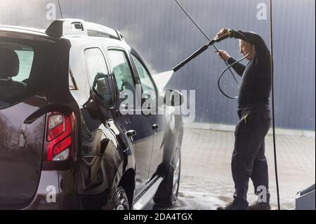 Un uomo lava la sua auto, un uomo a un autolavaggio, un autolavaggio Renault, Russia, regione di Kaliningrad, 1 marzo 2020 Foto Stock