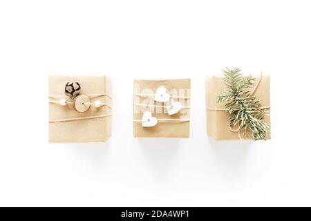 Natale handmade scatole regalo composizione artistica su superficie bianca. Regali, decorazioni natalizie in legno, rami di abete, cono di pino. Concetto fai-da-te fatto a mano Foto Stock
