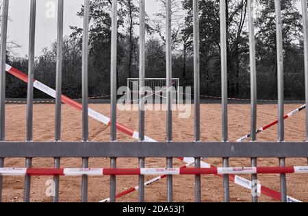 Guardando attraverso le barre di obiettivo a un campo di calcio duro che È chiuso a causa della pandemia di Coronavirus Foto Stock