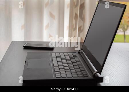 computer portatile e telefono cellulare su un tavolo pronti per il lavoro da casa e utilizzare nuove tecnologie e social network Foto Stock