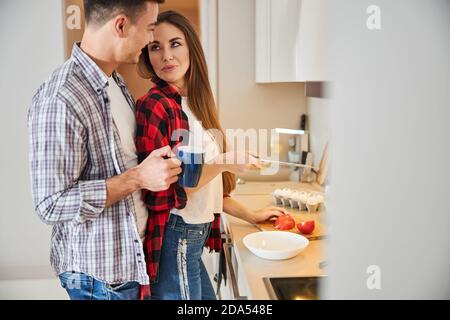Uomo con una tazza di caffè che sorride a sua moglie Foto Stock