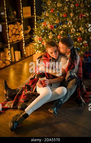 Sognante dolce coppia coccolarsi con cioccolata calda, così romantico, giù sul pavimento sulla plaid, festa invernale a intimità. Foto Stock