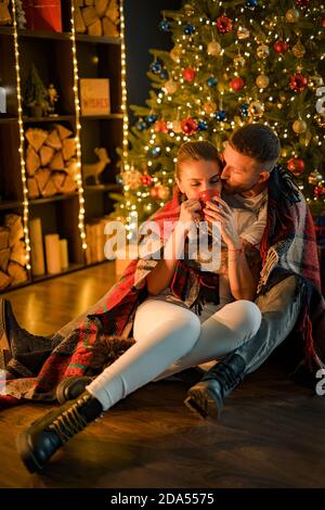 Sognante dolce coppia coccolarsi con cioccolata calda, così romantico, giù sul pavimento sulla plaid, festa invernale a intimità. Foto Stock