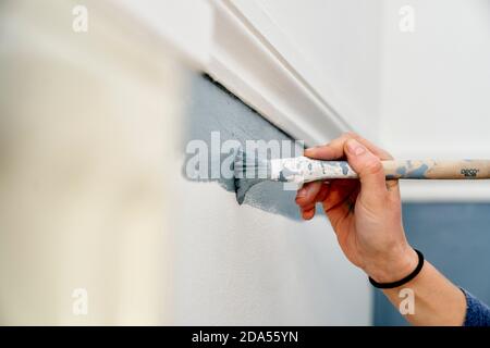 Primo piano della mano con un pennello per verniciare la parete Foto Stock