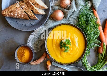 Deliziosa zuppa di carote cremosa con polvere di curcuma e baguette per colazione Foto Stock