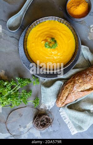 Deliziosa zuppa di carote cremosa con polvere di curcuma e baguette per colazione Foto Stock