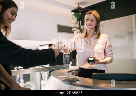 Il cliente effettua il pagamento con carta di credito al check-in presso la reception. Foto Stock