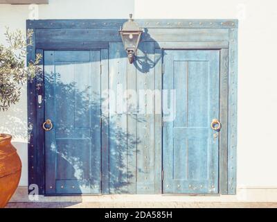 Porte in legno blu chiaro con maniglie rotonde dorate e. una lanterna nel mezzo Foto Stock