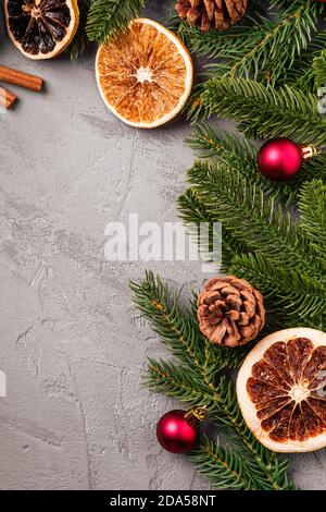 Composizione di Natale. Palline, cannella, anice, frutta secca, coni di pino e decorazioni ad aghi di abete su sfondo grigio. Spazio di copia vista dall'alto Foto Stock