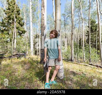 Ritratto di ragazzo di 7 anni in piedi nella foresta di Alberi di Aspen Foto Stock