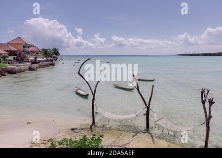 Due amache appese agli alberi, su una spiaggia tropicale a Bali, con una villa di lusso sullo sfondo Foto Stock