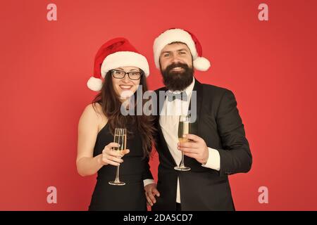 Festa di Natale del tempo. formale di coppia in amore festeggiare il nuovo anno. tuxedo uomo con la donna a santa hat. Buon Natale e saluti a tutti. business man e ragazza bere champagne. xmas party. Foto Stock