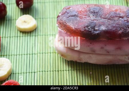 Gelato artigianale alla fragola e alla banana al mirtillo o ai pop-sicles foglie di menta verde decorate su un tavolo rustico, succo di frutta surgelato, stile vintage Foto Stock