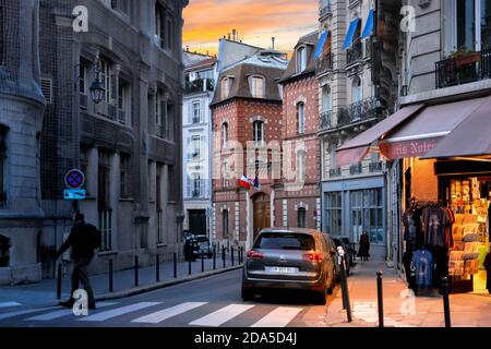 Una stretta e pittoresca strada a Île de la Cité a Parigi Francia come tramonta il sole e la luce proveniente da un negozio di souvenir brilla sul marciapiede Foto Stock
