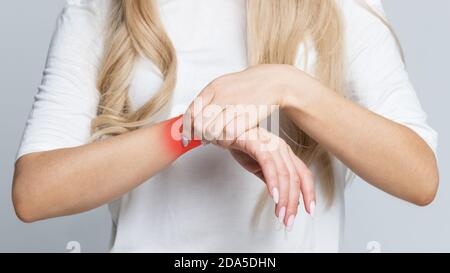 Closeup del braccio femminile che tiene il suo polso doloroso causato da lavoro prolungato sul computer, laptop / sindrome del tunnel carpale, artrite, malattie neurologiche Foto Stock
