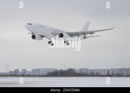 Aereo da passeggeri bianco che atterra all'aeroporto in inverno, basso sulla pista. Concetto di aviazione Foto Stock