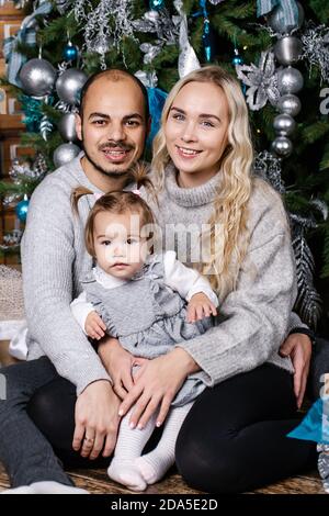 Felici i genitori con il bambino in camera decorata per Natale. Vacanza invernale Natale e Capodanno concetto Foto Stock