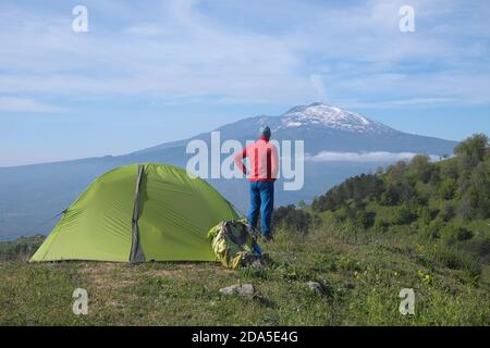 Uomo che guarda l'Etna vicino alla tenda verde, Sicilia Foto Stock