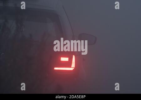 Luci di coda di un'auto in nebbia fitta, ora blu, sera nebbia, notte nebbia, auto Foto Stock