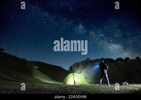 Uomo che punta la torcia blu alla montagna sotto il cielo stellato nel Parco dei Nebrodi, Sicilia Foto Stock